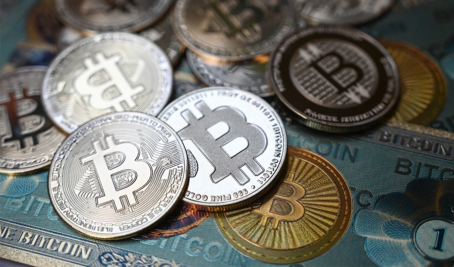 This illustration photograph taken on July 19, 2021 in Istanbul shows a physical banknote and coin imitations of the Bitcoin crypto currency. (AFP)