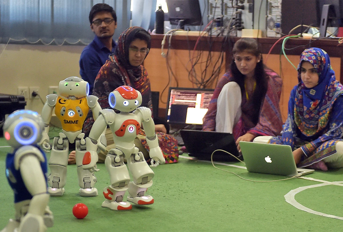 Pakistani students and team members of Robotics and Intelligence Systems Engineering (RISE) watch as their robot football players take part in a match at the engineering department of the National University of Sciences and Technology in Islamabad, Pakistan, on May 9, 2016. (AFP)