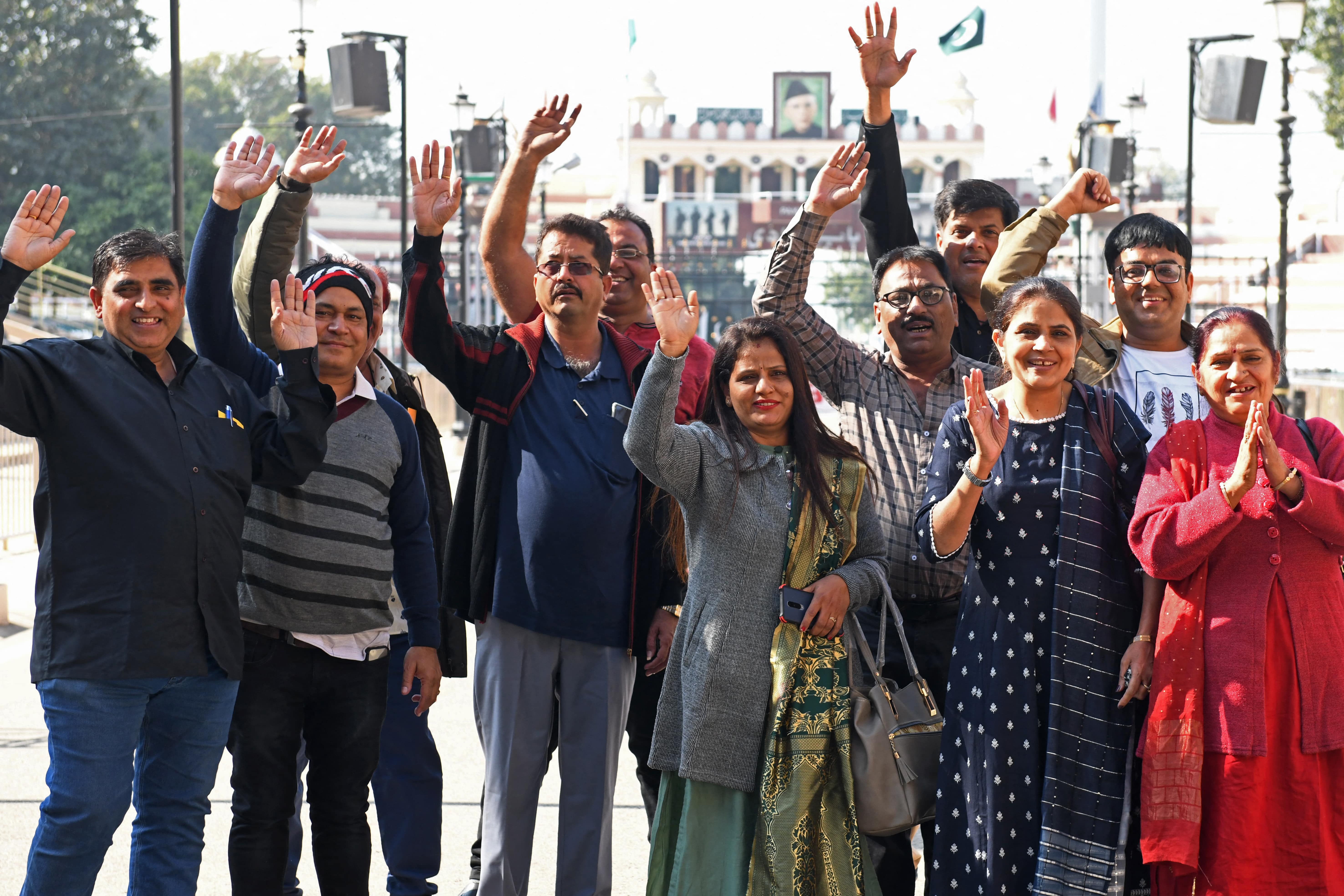Hindu pilgrims wave as they pose for pictures before crossing over to Pakistan to celebrate the birth anniversary of Satguru Sant Shadaram Sahib at the Puj Shadani Darbar Temple Hayat Pitafi, at the India-Pakistan border in Wagah, about 35km from Amritsar on December 4, 2021. (AFP)