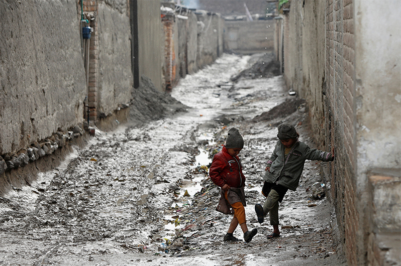 Children play along a muddy street after rain in Peshawar, Pakistan January 5, 2022. (REUTERS)