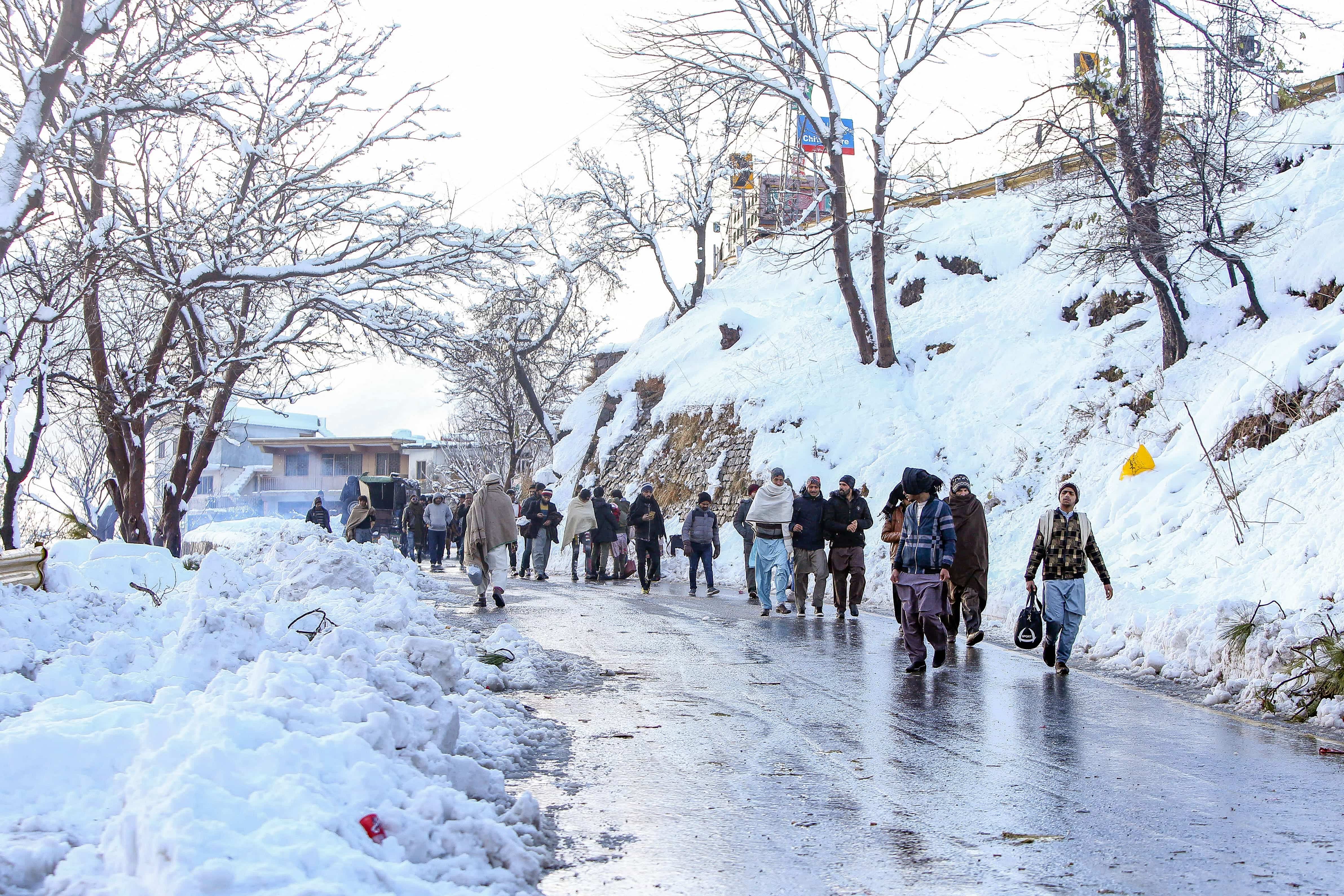Local tourists walk along a road after a heavy snowfall in Murree, around 70 kilometres (45 miles) northeast of the capital, Islamabad on January 8, 2022. (AFP)
