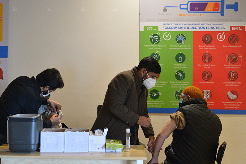 Health workers inoculate men with a dose of the Covid-19 coronavirus vaccine in Islamabad on January 4, 2022. (AFP)