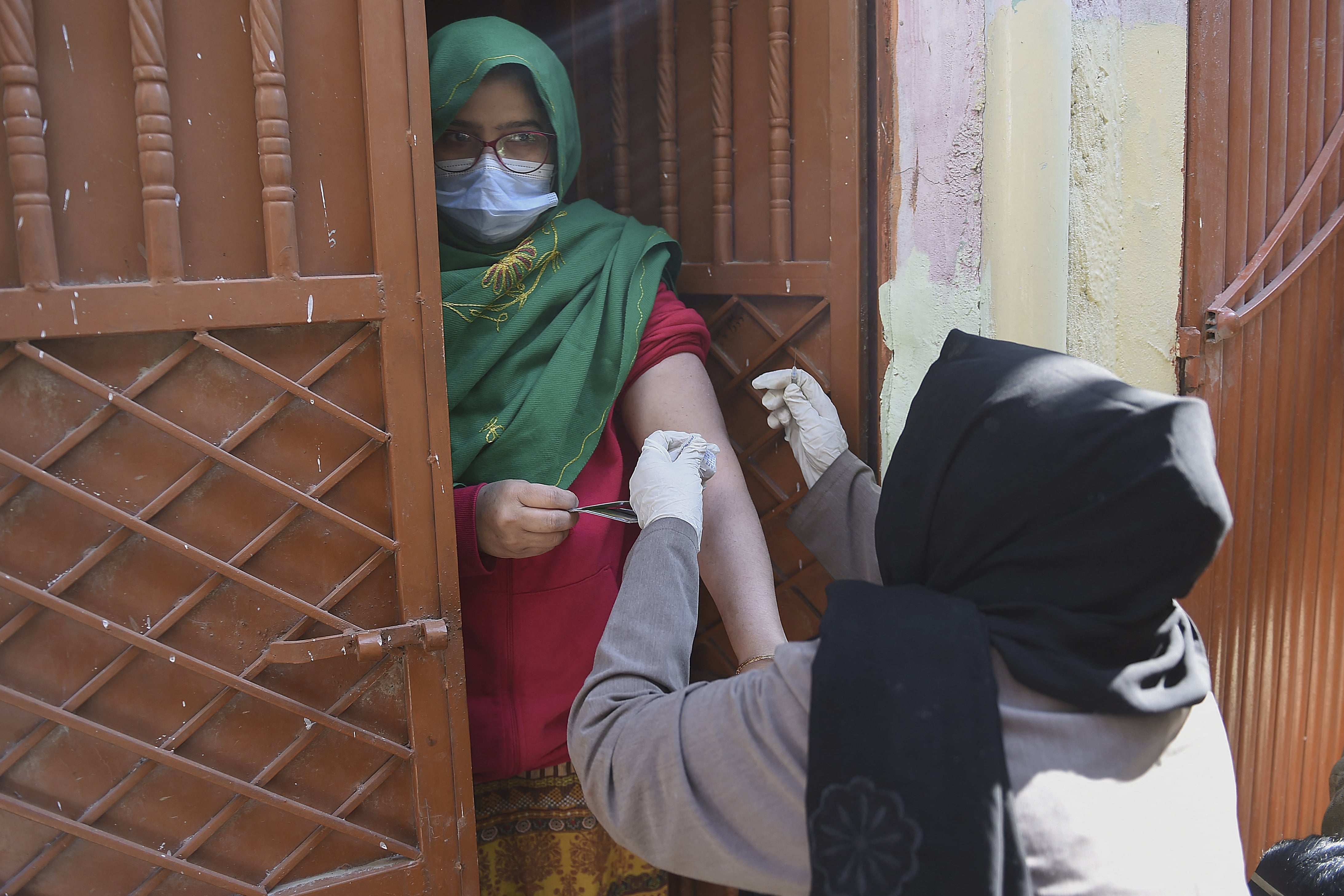 A health worker (R) inoculates a woman with a dose of the Covid-19 coronavirus PakVac vaccine during door to door vaccination in Karachi on January 11, 2022. (AFP)