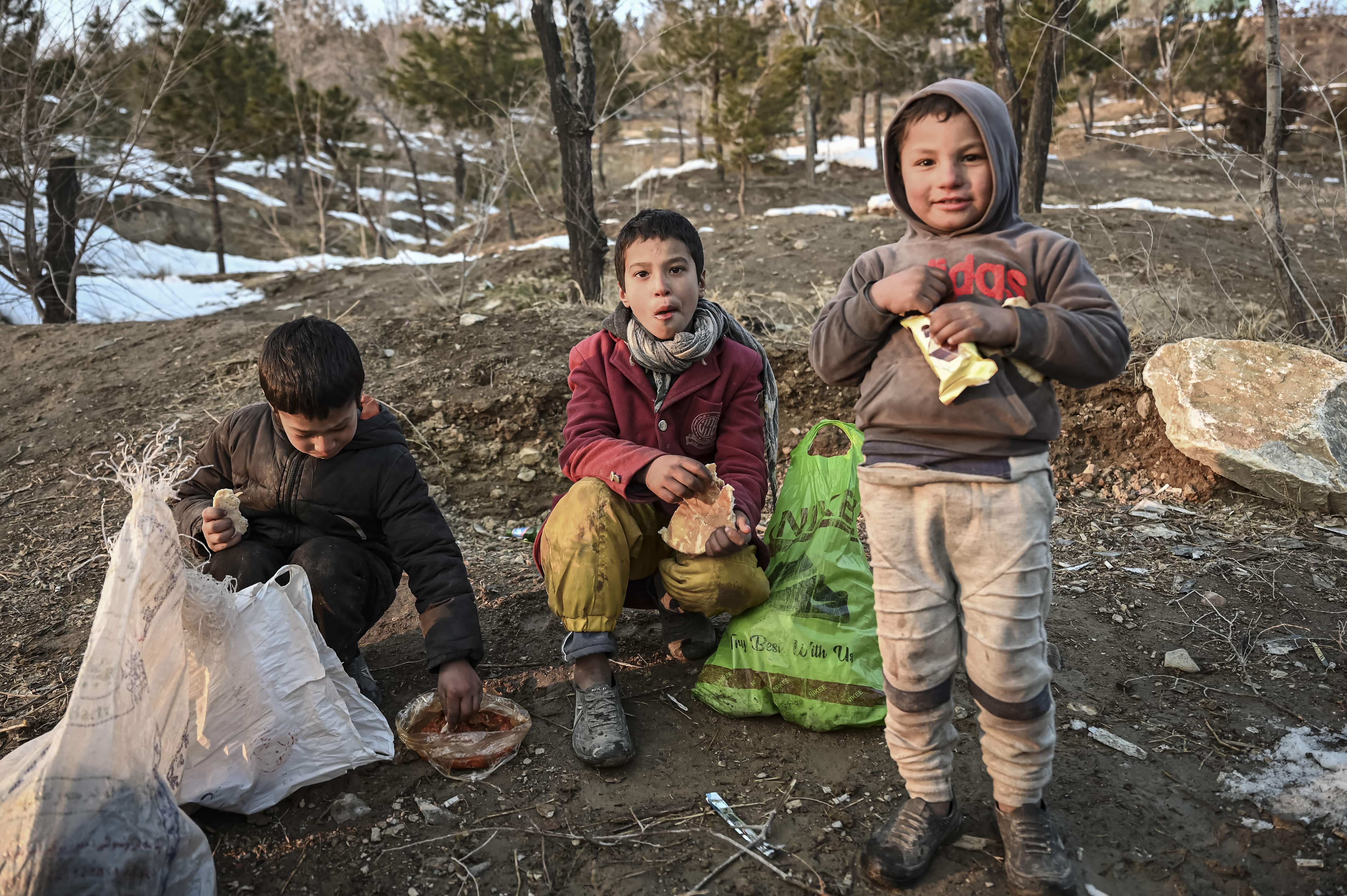 Children eat bread at the Wazir Akbar Khan hill on January 11, 2022. (AFP)