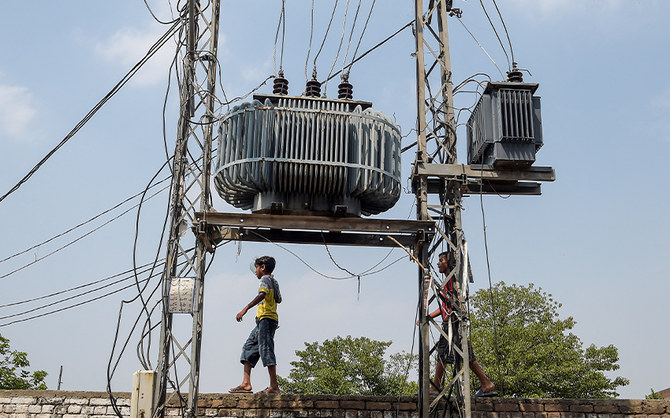 Two boys walk on a wall near high voltage electricity wires in Rawalpindi, Pakistan, on July 8, 2020. (AFP/File)