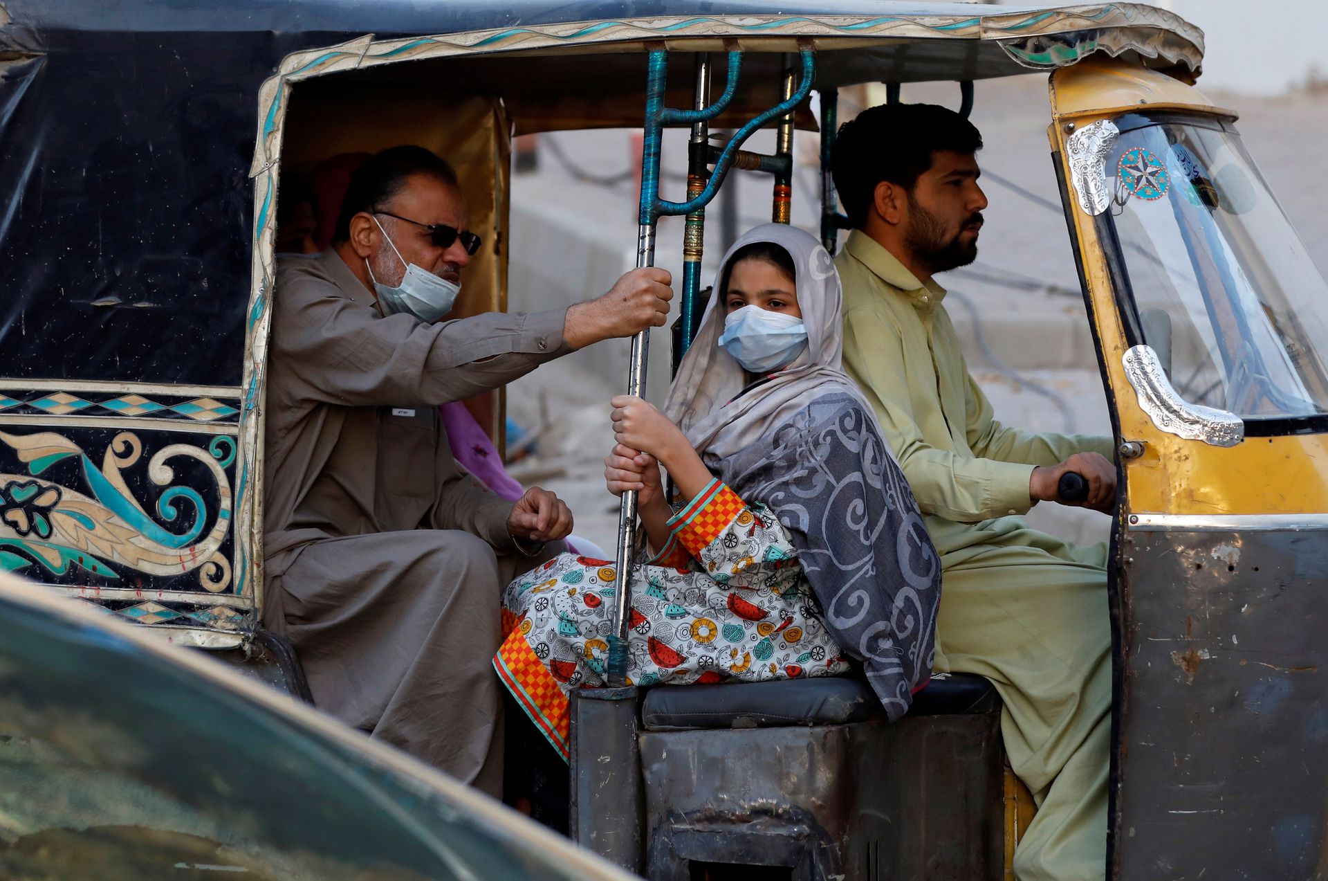 People with masks against COVID-19 travel by rikshaw (tok tok) in Karachi, Pakistan January 25, 2021. (REUTERS)