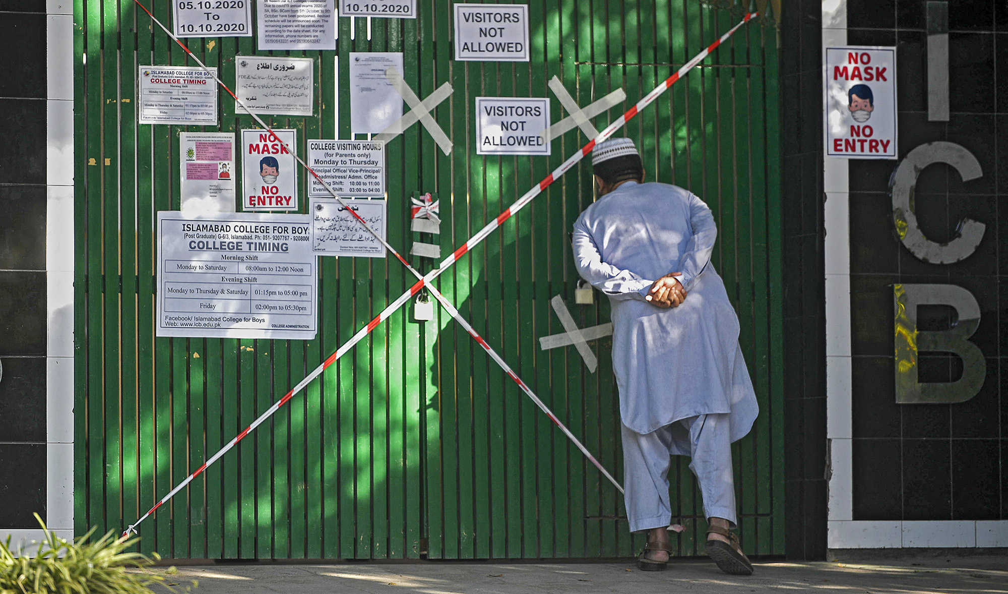 A man looks inside from a closed gate of a school sealed by authorities as some teachers and students tested positive for the Covid-19 Coronavirus in Islamabad on October 5, 2020. (AFP/File)