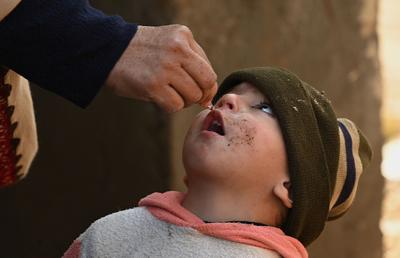 In this picture taken on January 24, 2022, a health worker administers polio vaccine drops to a child during a door-to-door polio vaccination campaign on the outskirts of Mardan, in Pakistan's Khyber Pakhtunkhwa province. (AFP)