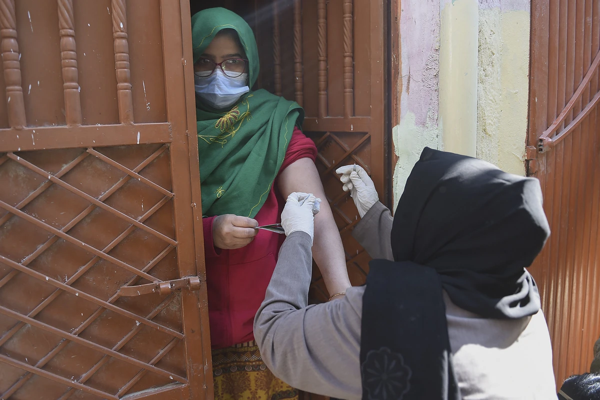 A health worker (R) inoculates a woman with a dose of the Covid-19 coronavirus PakVac vaccine during door to door vaccination in Karachi on January 11, 2022. (AFP)