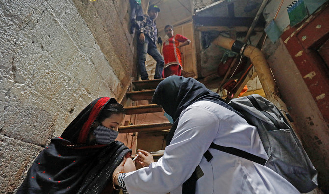 A healthcare worker administers a dose of COVID-19 vaccine during a door-to-door vaccination campaign in a slum in Karachi, Pakistan, on January 13, 2022. (REUTERS)
