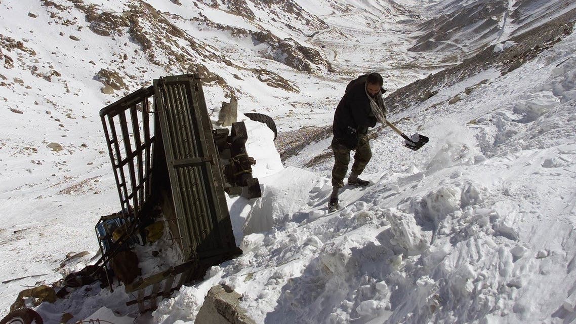 An Afghan driver clears snow from around his truck after it was swept off the road by an avalance on the south side of Salang tunnel, some 100 km north from Kabul, on February 10, 2010 (REUTERS/File)
