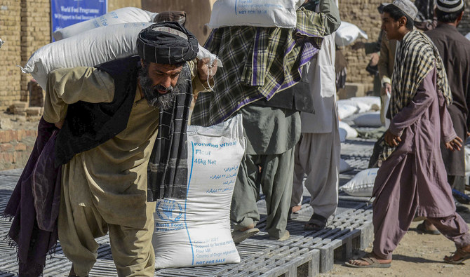 Afghan people carry sacks of food grains distributed as an aid by the World Food Programme (WFP) in Kandahar, Afghanistan, on October 19, 2021. (AFP/File)
