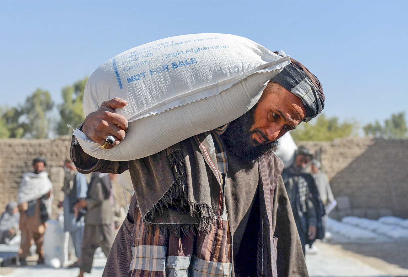Afghan people carry sacks of food grains distributed as an aid by the World Food Programme (WFP) in Kandahar on October 19, 2021. (AFP/File)
