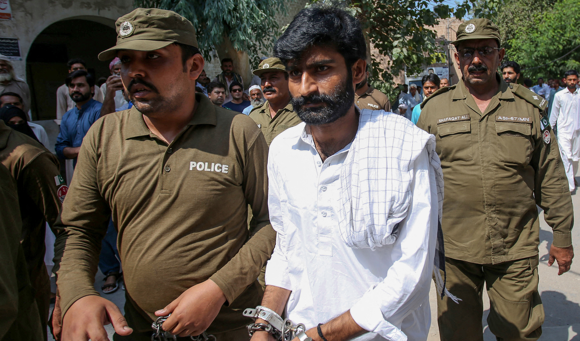 Policemen escort hand-cuffed Muhammad Waseem, center, brother of slain social media celebrity Qandeel Baloch, as he leaves the court after the verdict in Multan on September 27, 2019. (AFP/File)