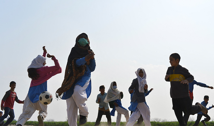 Children learn how to play football outside their school on the outskirts of Islamabad on February 15, 2022. (AFP)