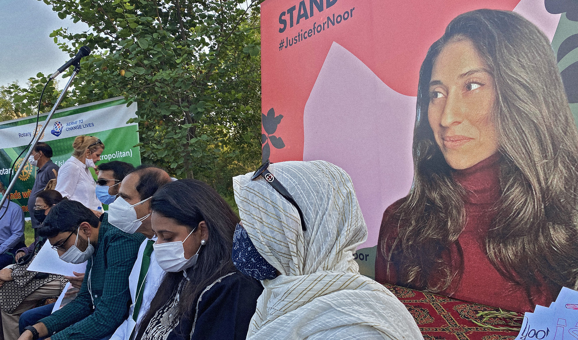 Family members of Noor Mukadam sit in front of a poster with her photo during a vigil in Islamabad, Pakistan on September 22, 2021. (AN photo/File)