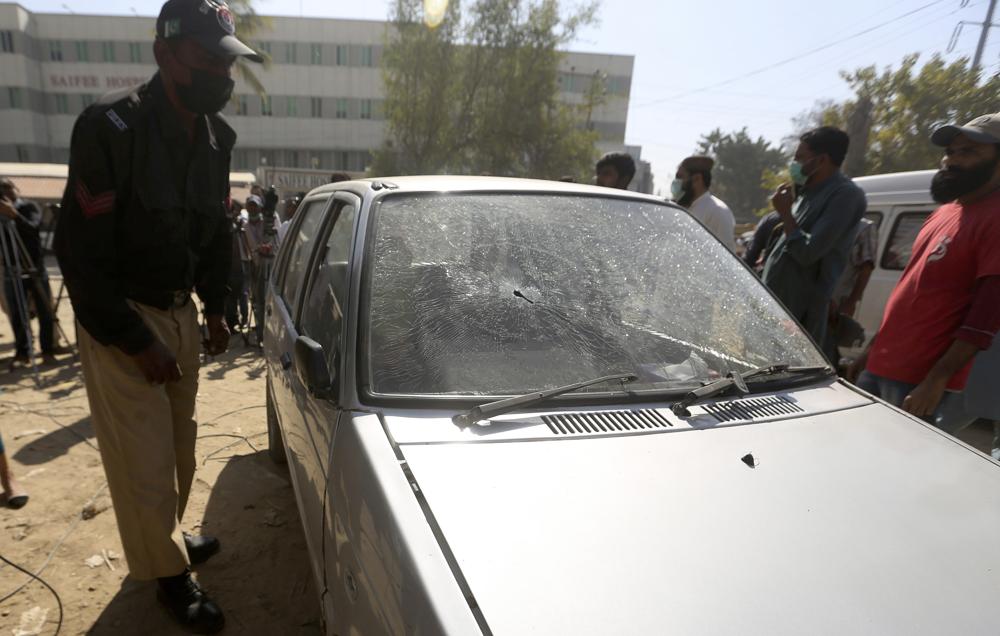 A police officer examines a bullet-riddled car of TV producer Athar Mateen, who was killed by robbers in Karachi, Pakistan, Friday, Feb. 18, 2022. (AP)