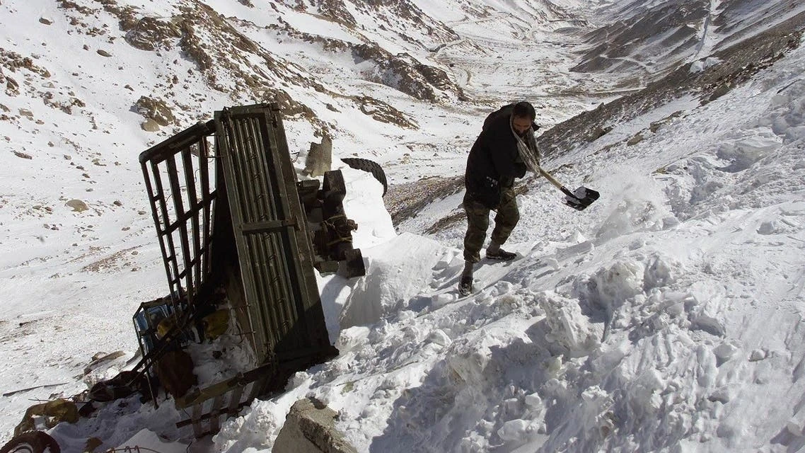 An Afghan driver clears snow from around his truck after it was swept off the road by an avalance on the south side of Salang tunnel, some 100 km north from Kabul, on February 10, 2010 (REUTERS/File)