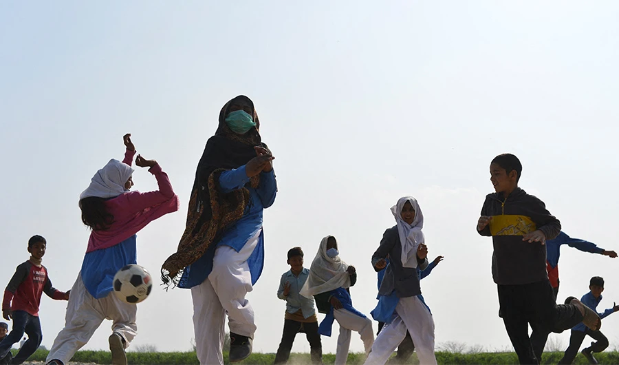 Children learn how to play football outside their school on the outskirts of Islamabad on February 15, 2022. (AFP)