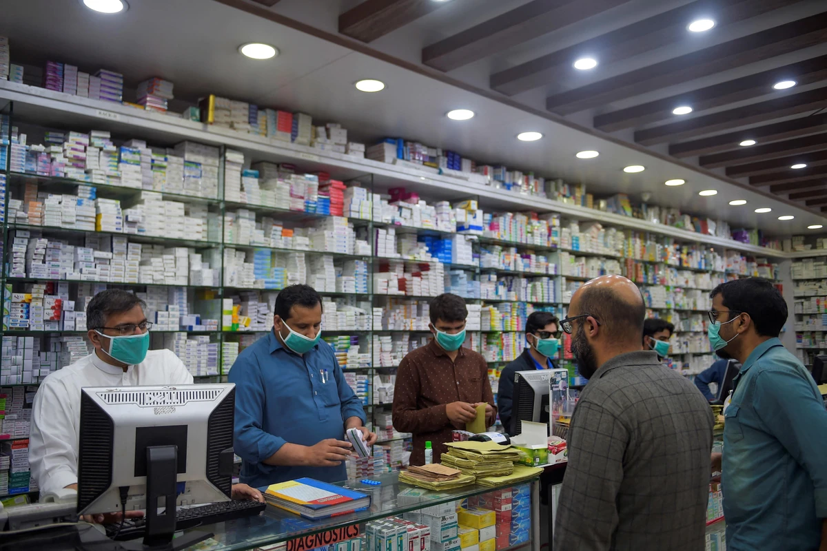 Pharmacy employees wearing facemasks as a preventive measure against the COVID-19 coronavirus attend to customers in Islamabad on March 23, 2020. (AFP)