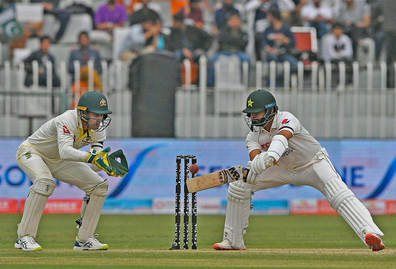 Pakistan's Azhar Ali (R) plays a shot as Australia's wicketkeeper Alex Carey watches during the second day of play of the first Test cricket match in Rawalpindi on March 5, 2022. (AFP)