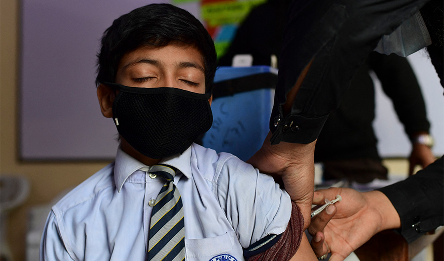 A health worker inoculates a student with a dose of the Pfizer vaccine against the Covid-19 coronavirus at his school in Karachi on January 24, 2022. (AFP)