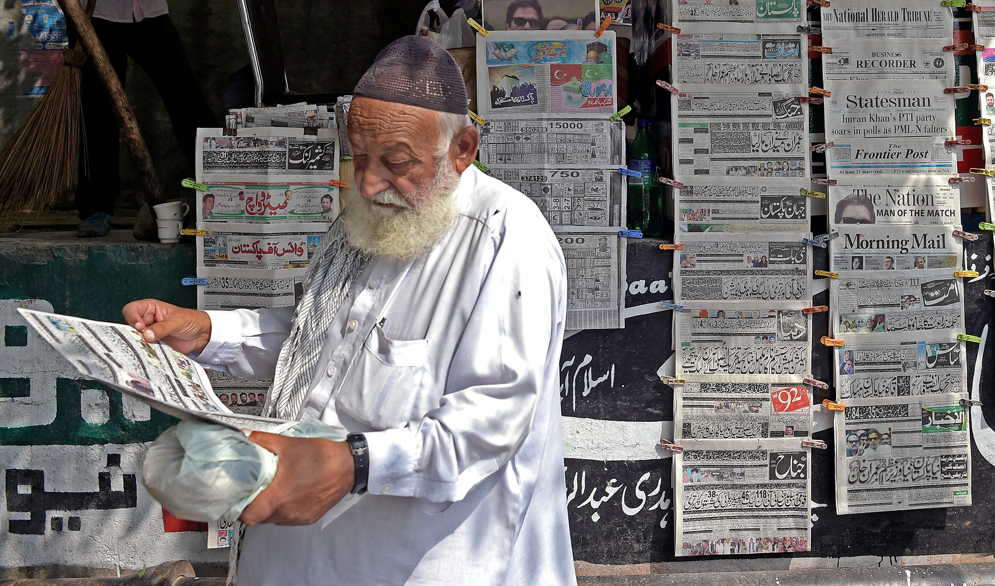 A Pakistani resident reads a morning newspaper at a stall in Islamabad on July 26, 2018. (AFP/File)