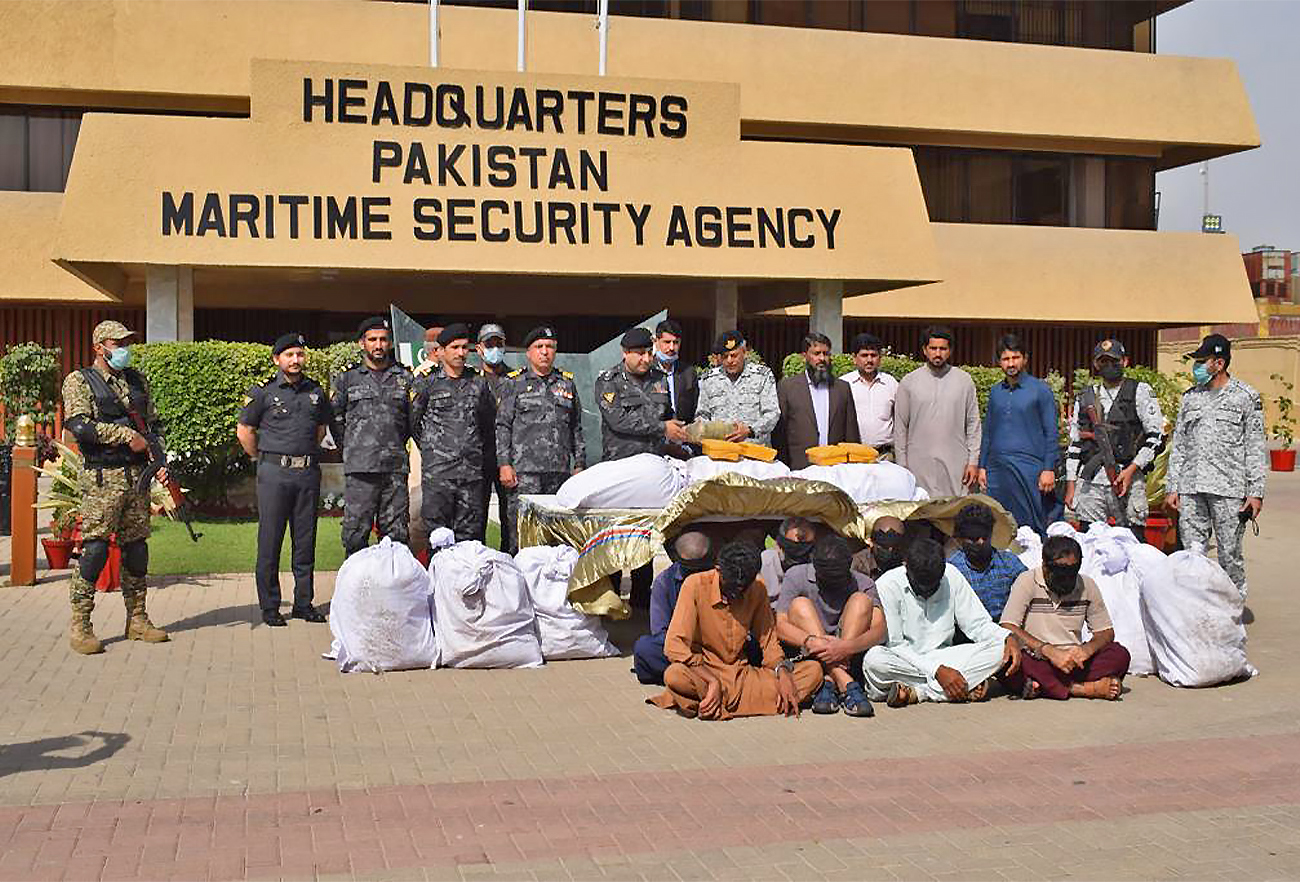 Officials of Pakistan Maritime Security Agency pose for a pictures with seized narcotics and smugglers in Karachi, Pakistan, on March 7, 2022. (Pakistan Maritime Security Agency)