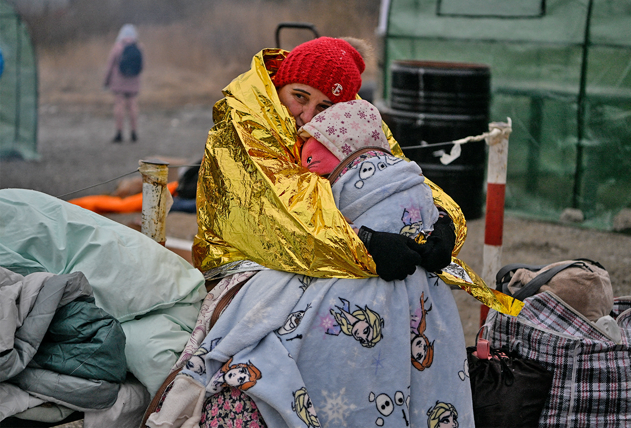 A woman hugs her grandaugther as people wait in freezing cold temperatures to be transferred to a train station, after crossing the Ukrainian borders into Poland, at the Medyka border crossing in Poland, on March 7, 2022. (AFP)