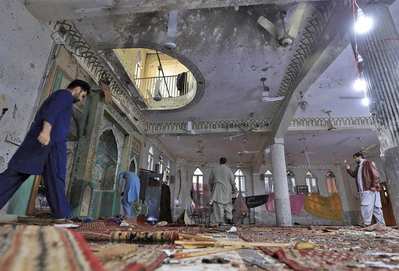 People walk amid the damages at the prayer hall after a bomb blast inside a mosque during Friday prayers in Peshawar, Pakistan, on 4 March 2022. (REUTERS)