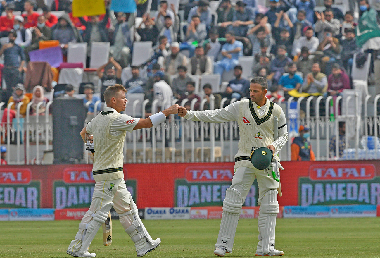 Australia's David Warner (L) and teammate Usman Khawaja bumps fists as they walk back to pavilion during lunch break on the third day of the first Test cricket match between Pakistan and Australia in Rawalpindi on March 6, 2022. (AFP)