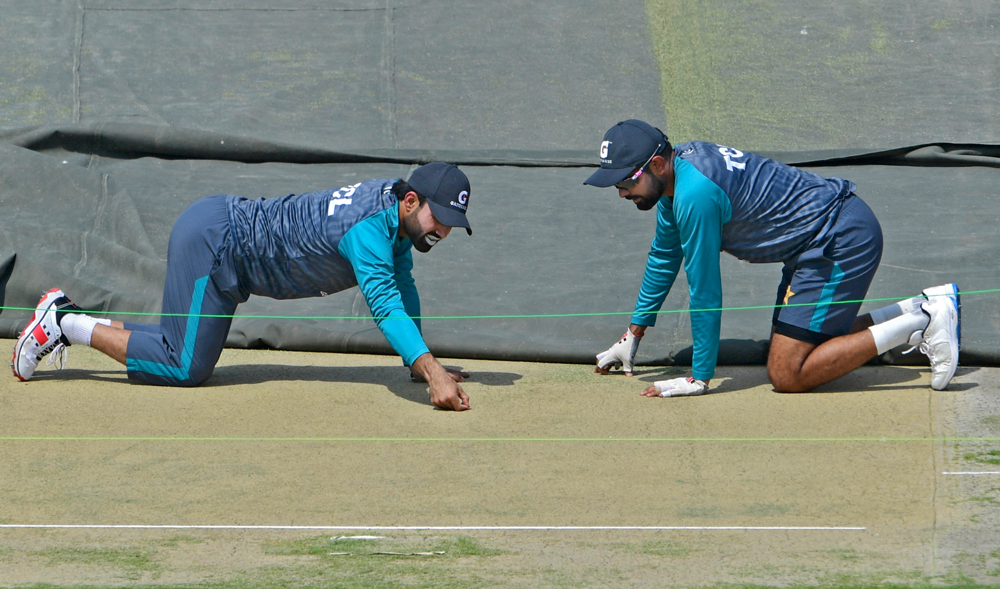 Pakistan's captain Babar Azam, right, and teammate Mohammad Rizwan inspect the pitch during a practice session at the National Cricket Stadium in Karachi on March 10, 2022, ahead of their second cricket Test match against Australia. (AFP)