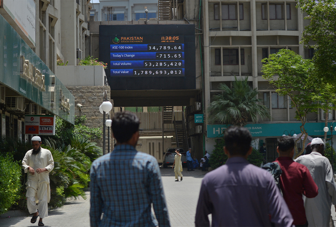 Pakistani people walk past a screen with share prices outside the Pakistan Stock Exchange (PSX) in Karachi on June 10, 2019. (AFP/File)