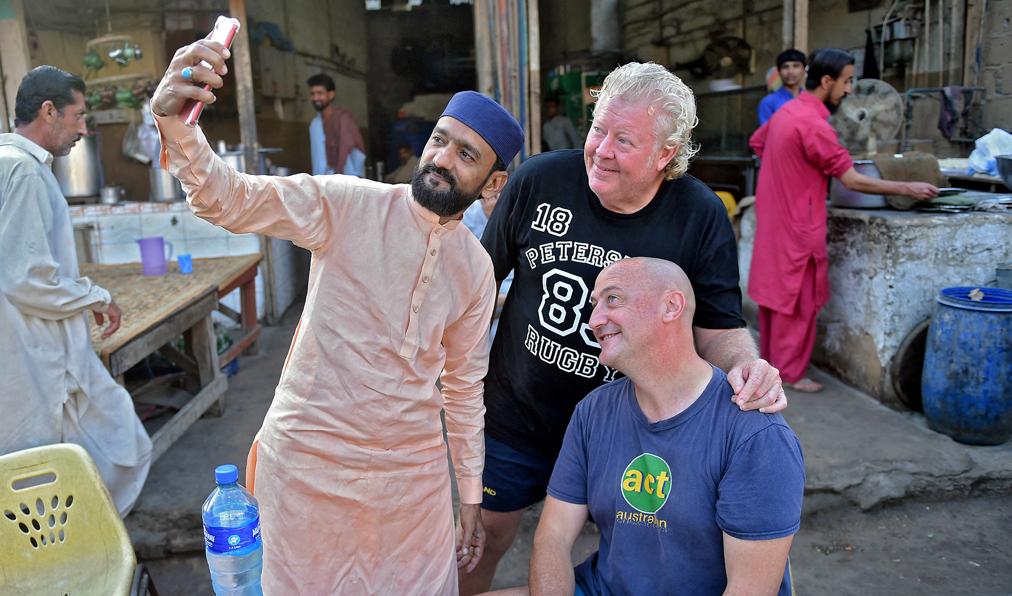A local resident poses for a selfie with Australian cricket fan Luke Gillian, sitting, in Karachi, Pakistan, on March 13, 2022. (AFP)