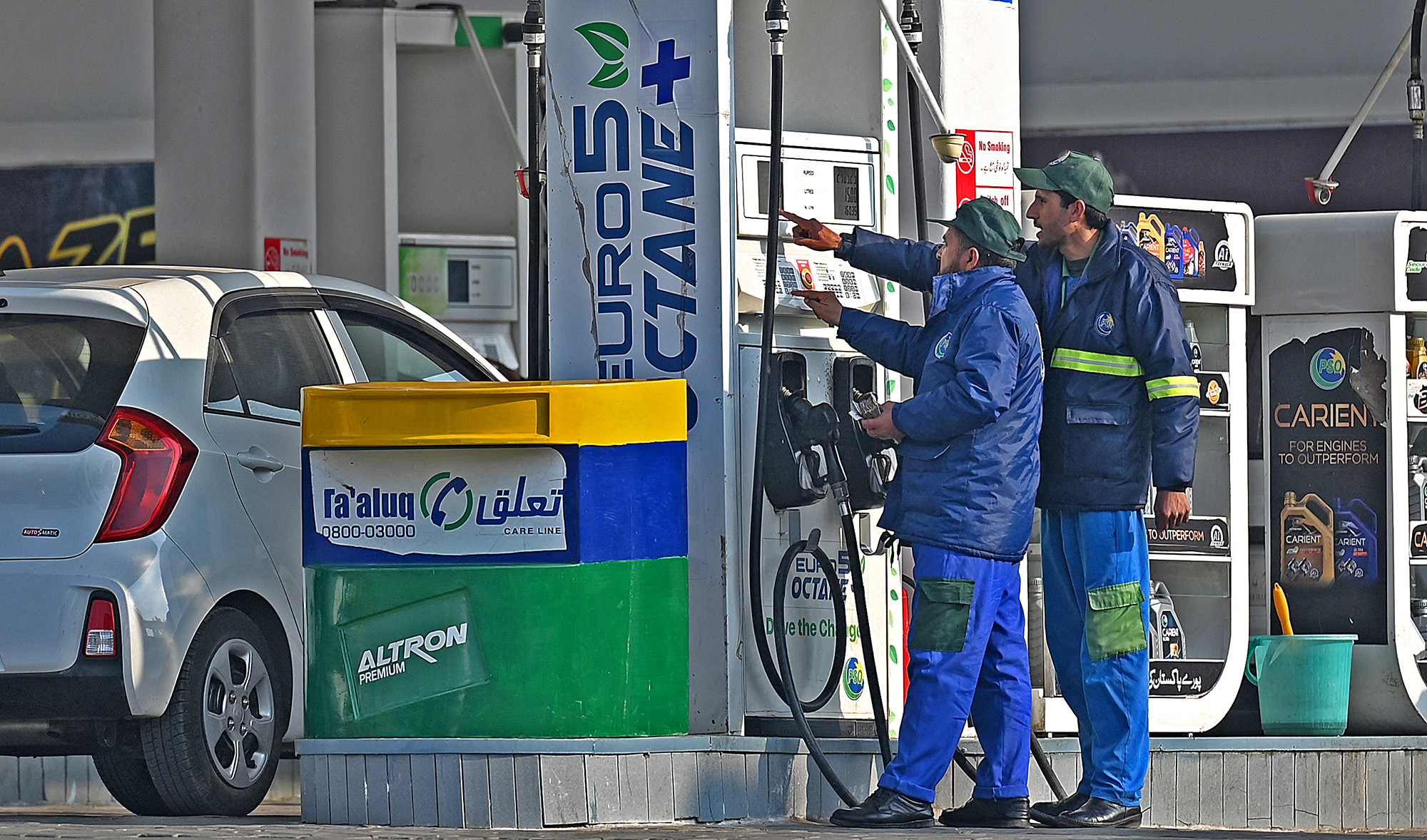 Employees at a fuel station attend to their customers in Islamabad on February 16, 2022, after a hike in prices of petroleum products. (AFP/File)
