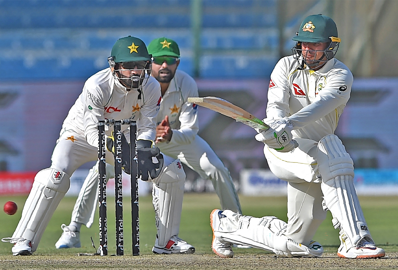 Australia's Usman Khawaja (R) plays a shot as Pakistan's wicketkeeper Mohammad Rizwan watches during the first day of the second Test cricket match between Pakistan and Australia in Karachi on March 12, 2022. (AFP/File)