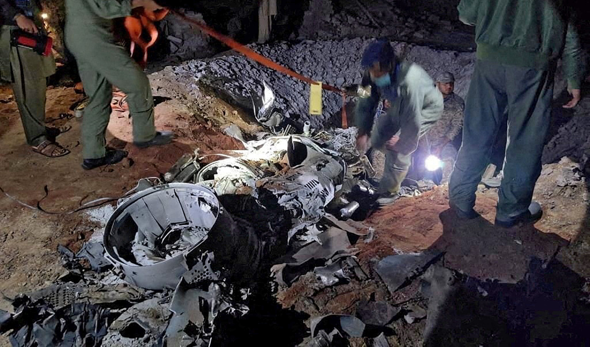 People work around what Pakistani security sources say is the remains of a missile fired into Pakistan from India, near Mian Channu, Pakistan, March 9, 2022. (Pakistan security forces via Reuters)
