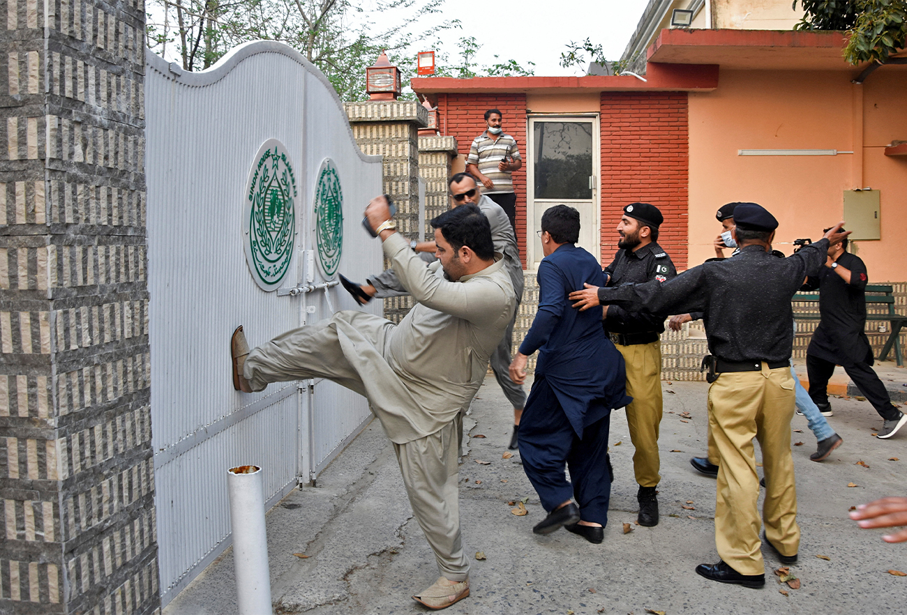 Police officers try to stop the supporters of the ruling political party Pakistan Tehreek-e-Insaf (PTI), as they stormed in protesting at the entrance of the Sindh House in Islamabad, Pakistan March 18, 2022. (REUTERS)