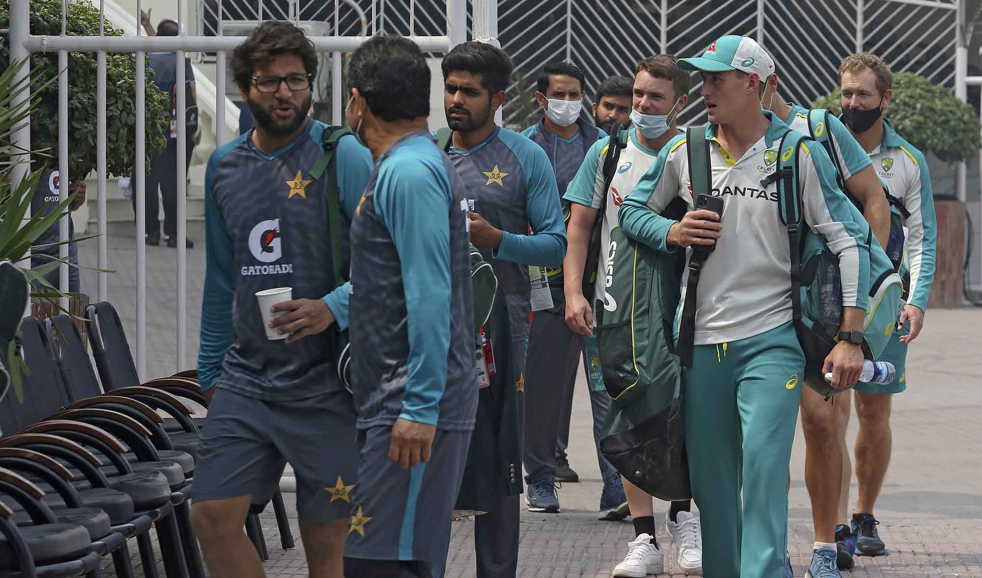 Pakistani players, left, and Australia's cricket team arrive to attend practice session at the Gaddafi Stadium in Lahore, Pakistan, on March 20, 2022. (AP)