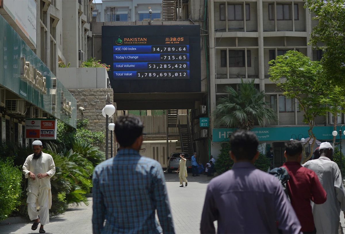 Pakistani people walk past a screen with share prices outside the Pakistan Stock Exchange (PSX) in Karachi on June 10, 2019. (AFP/File)