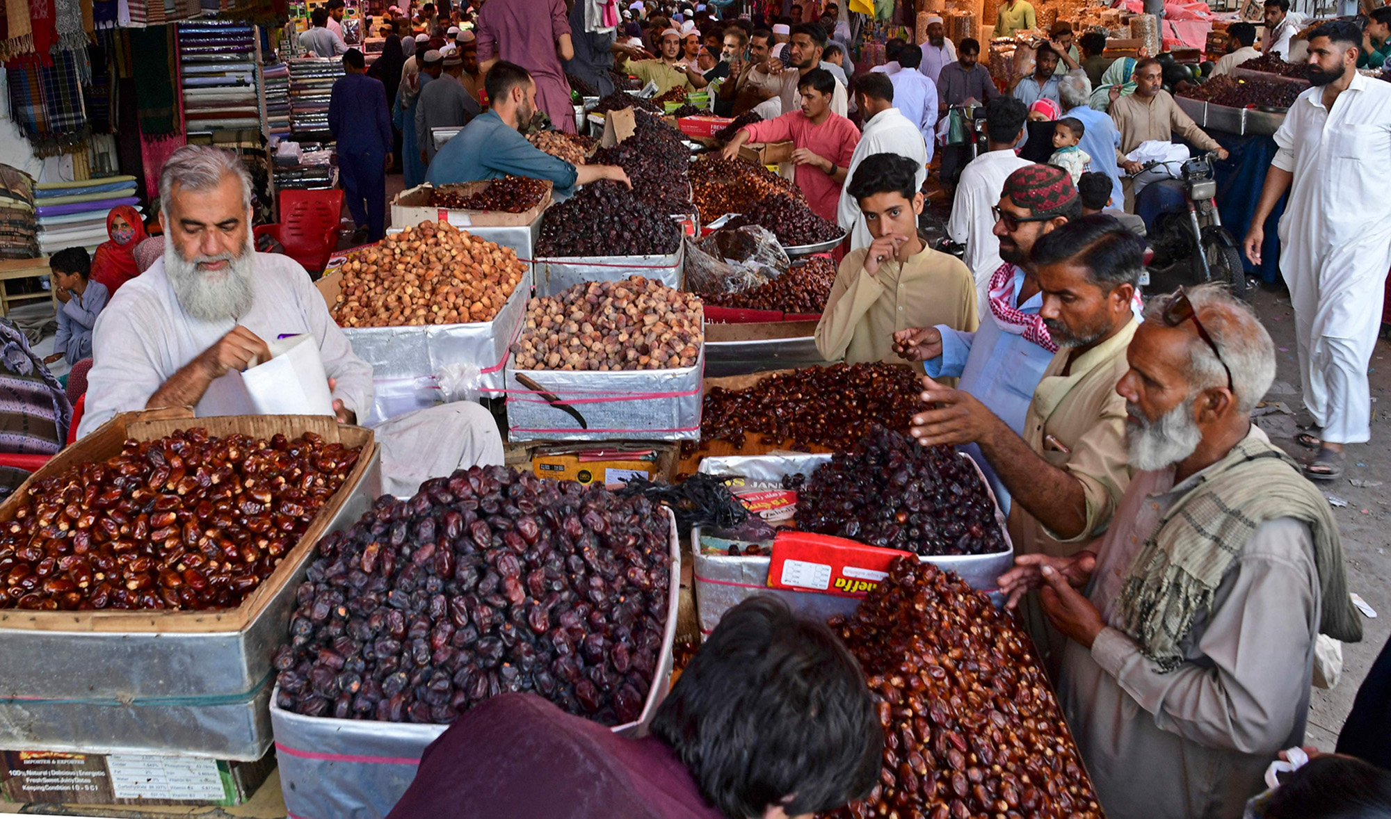 Muslim men buy dates at a market ahead of the Muslim fasting month of Ramadan, in Karachi on April 1, 2022. (AFP)