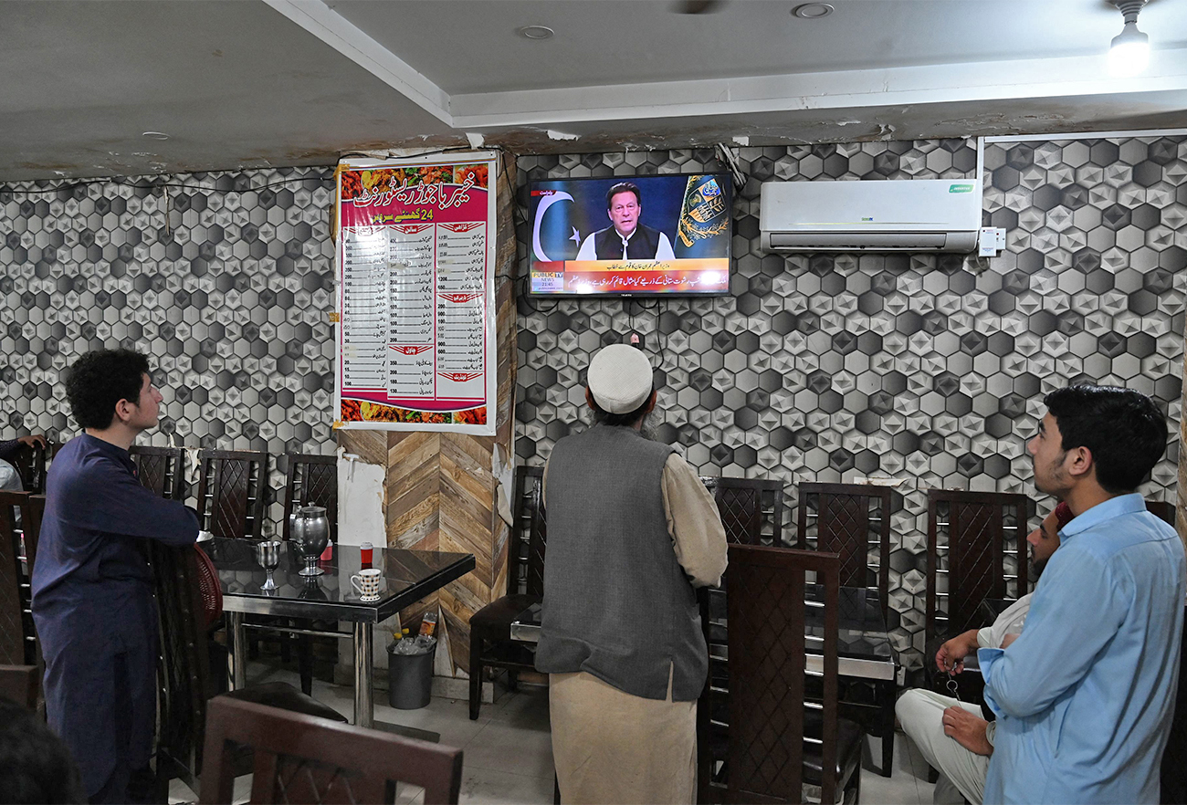 People listen to Pakistan's Prime Minister Imran Khan addressing the nation on television at a restaurant in Islamabad, Pakistan, on April 8, 2022. (AFP)