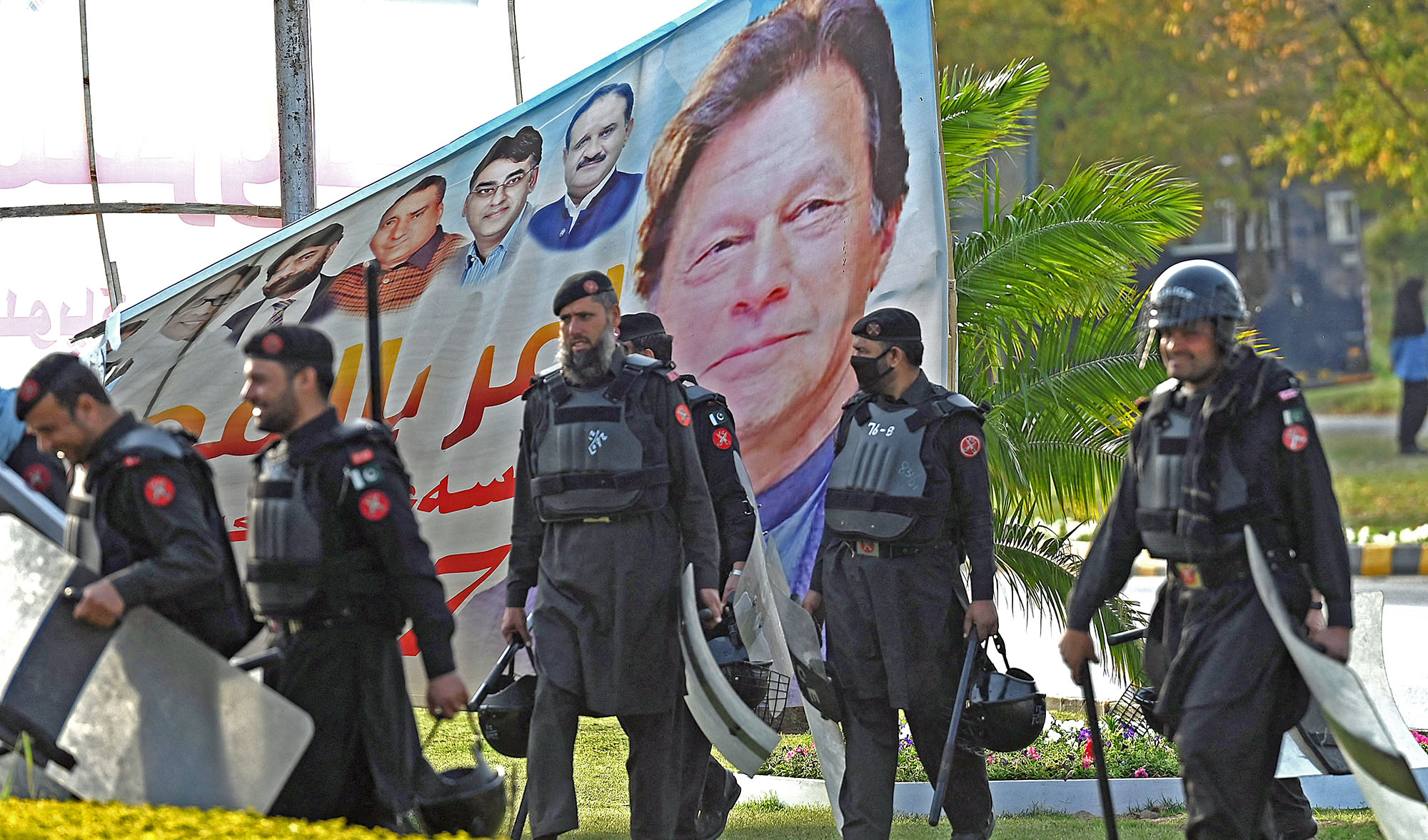 Security personnel walk past a banner featuring an image of Pakistan's Prime Minister Imran Khan near Parliament House building in Islamabad on April 3, 2022. (AFP/File)