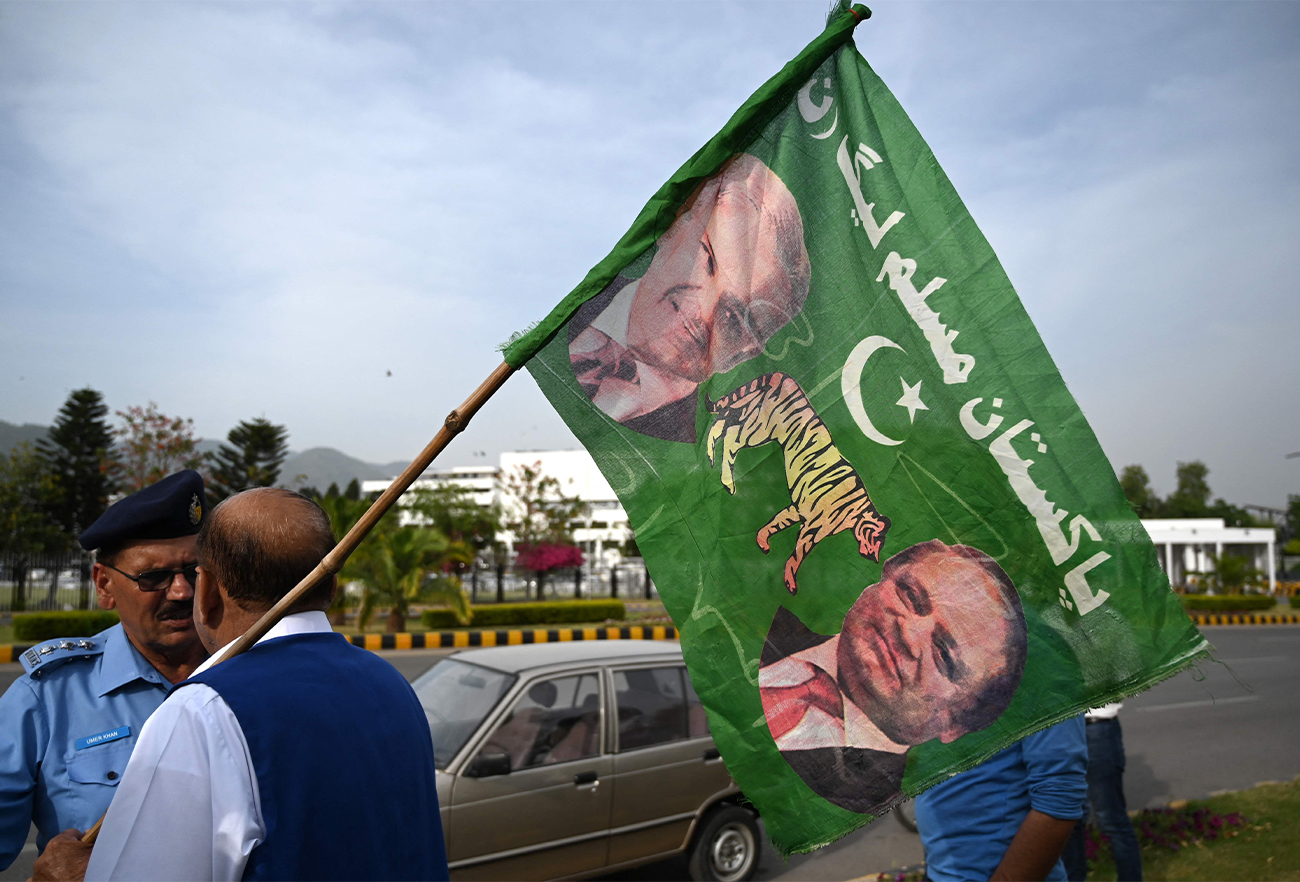 A supporter of Pakistan Muslim League-N (PML-N) holds a party flag with images of Shehbaz Sharif and his elder brother and former prime minister Nawaz Sharif outside the parliament house building in Islamabad, Pakistan, on April 11, 2022. (AFP)