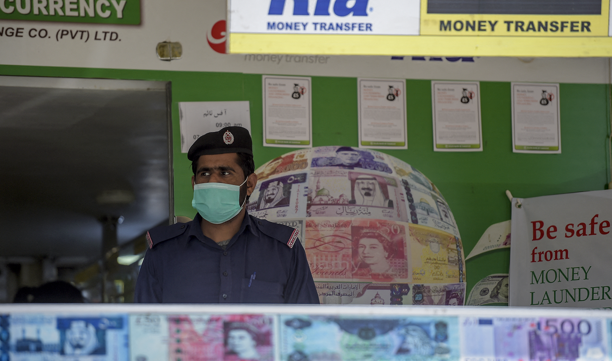 A security guard wearing a facemask stands guard outside a currency exchange shop in Rawalpindi, Pakistan, on March 18, 2020. (AFP/File)