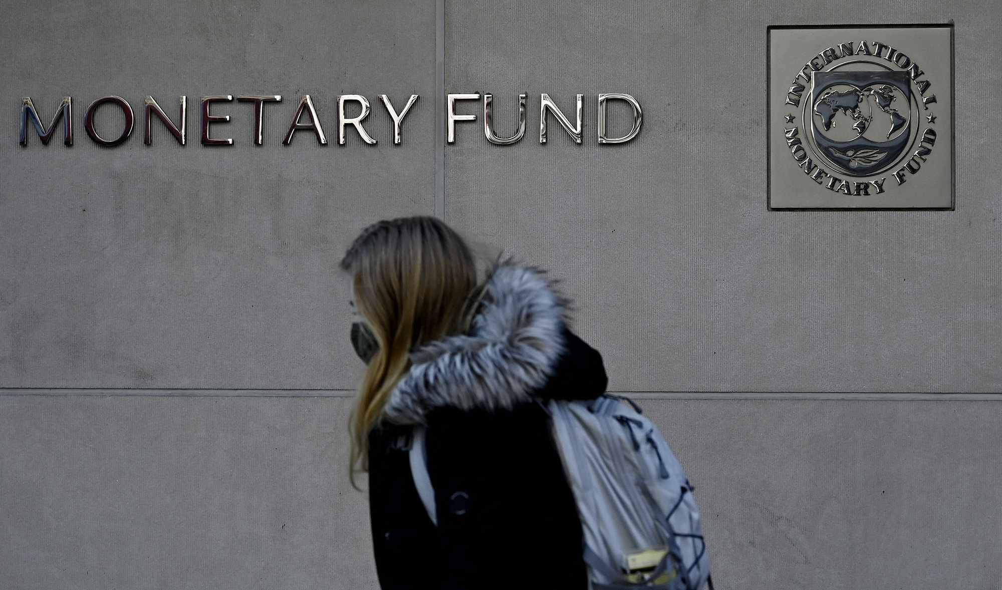 A woman walks past the International Monetary Fund headquarters in Washington, DC, on January 26, 2022. (AFP/File)