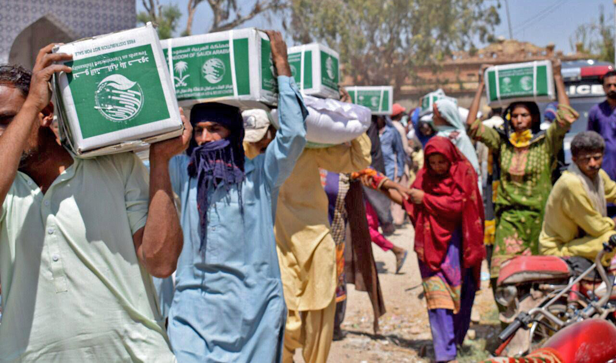 In this photograph shared by the Saudi embassy on April 17, 2022, people carry food packages delivered to them by King Salman Humanitarian Aid & Relief Centre (KSRelief). (Photo courtesy: KSA Embassy in Islamabad)