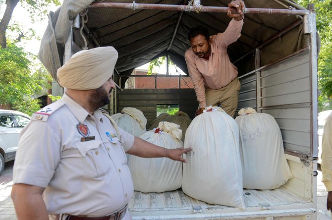 Indian Punjab Police personnel and workers unload bags of suspected heroin and suspected mixed narcotics from a truck to be brought to the court, in Amritsar on June 30, 2019. (AFP/FILE)