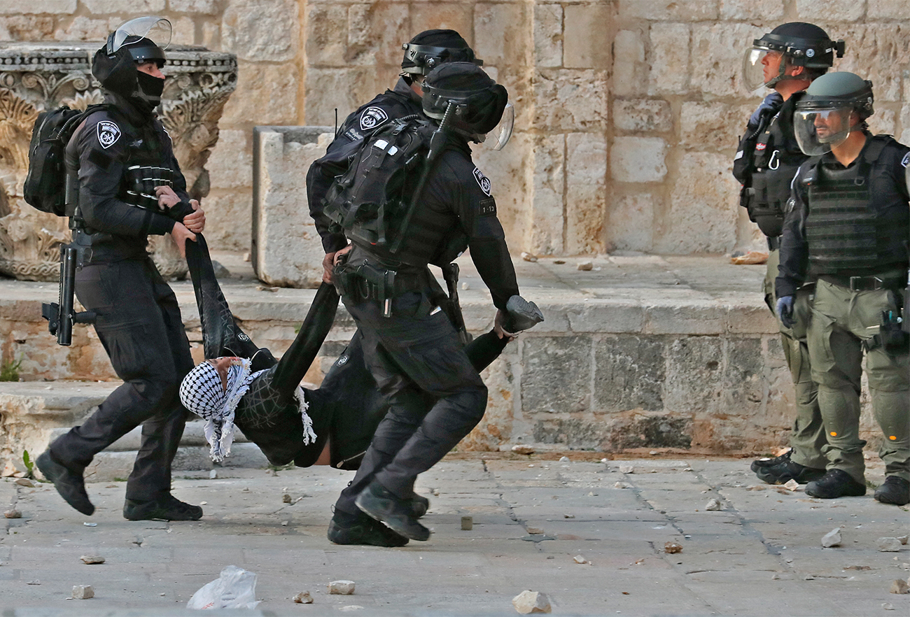 Israeli police carry a wounded young Palestinian demonstrator at Jerusalem's Al-Aqsa mosque compound on April 22, 2022. (AFP)