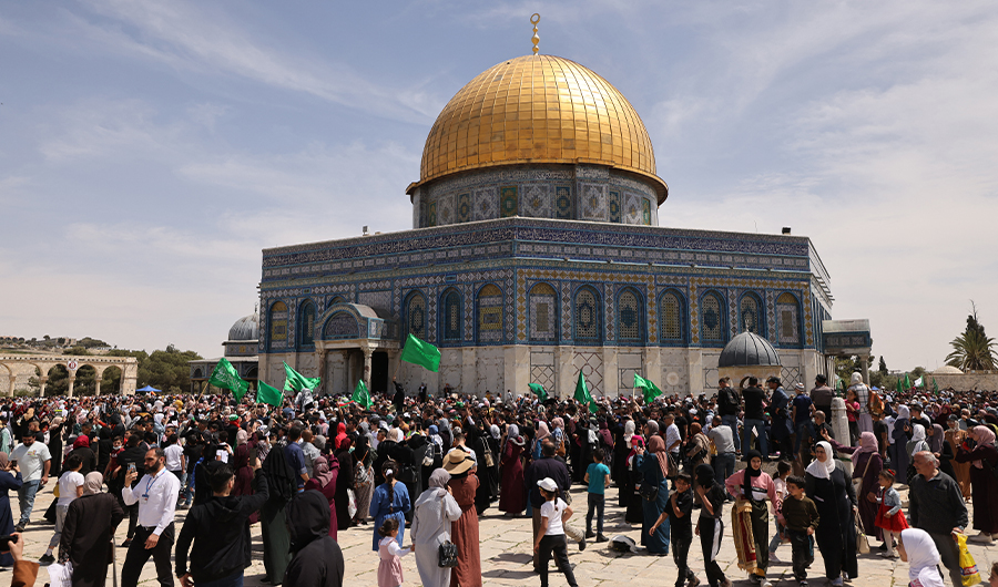 Palestinians wave Islamic flags as they gather in front of the Dome of the Rock mosque inside Jerusalem's Al-Aqsa Mosque complex following Friday prayers on April 22, 2022. (AFP)